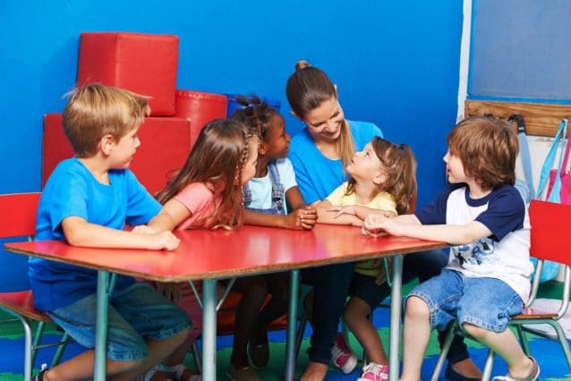 Children and teacher sitting around a table.
