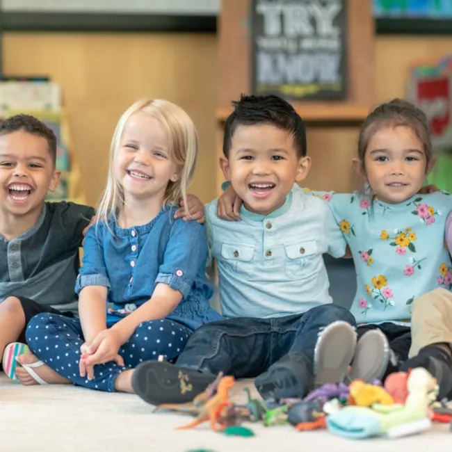 Children sitting and smiling in a classroom.
